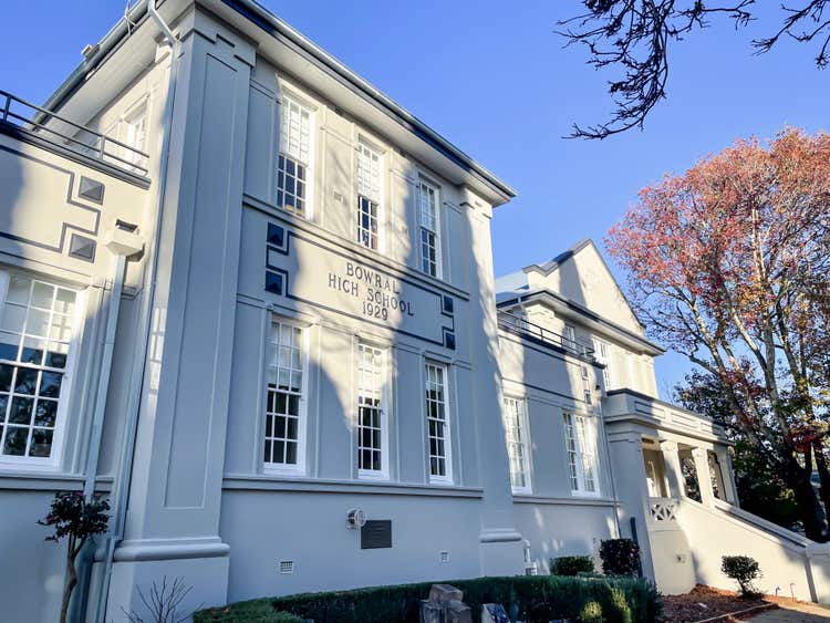 Bowral High School building, established 1929, with large white windows and autumn trees.